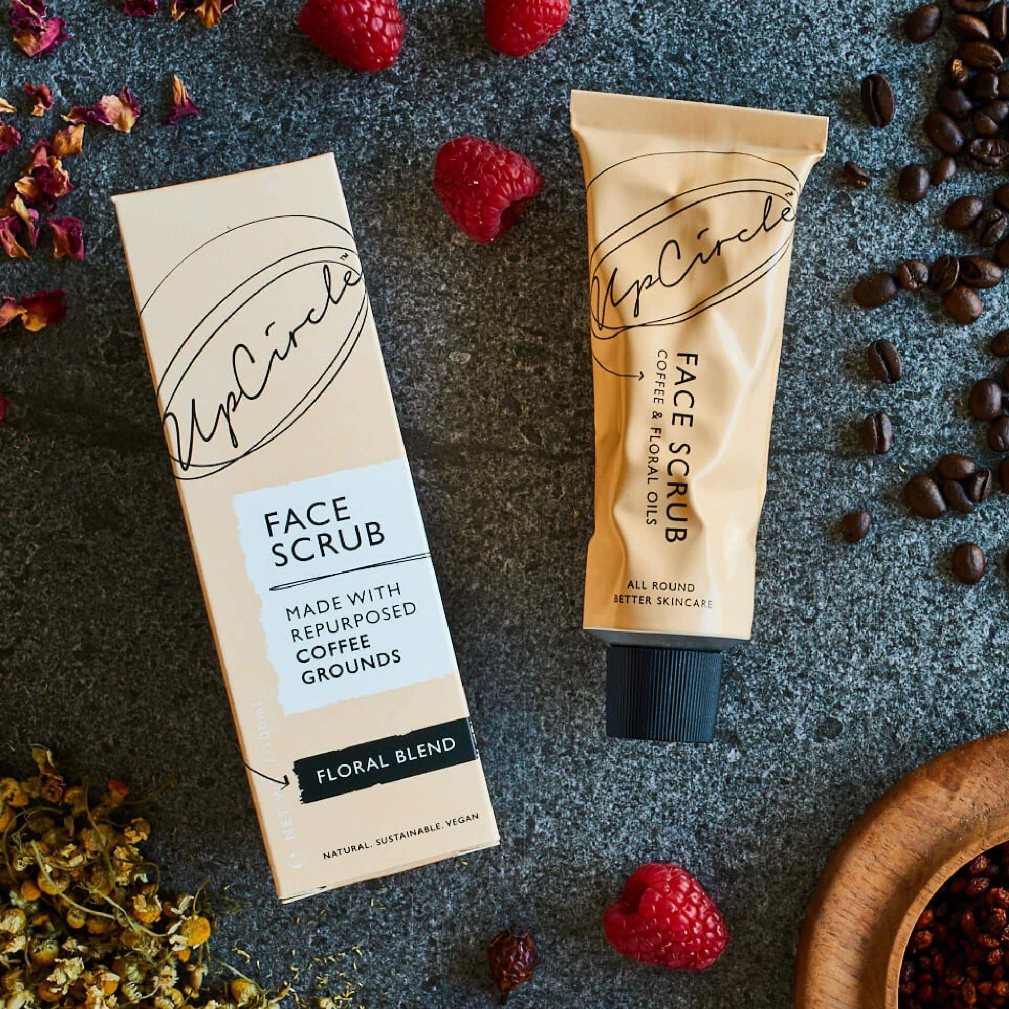 UpCircle face scrub of coffee and floral oils aluminum tube with its package next to it and spices surrounding.
